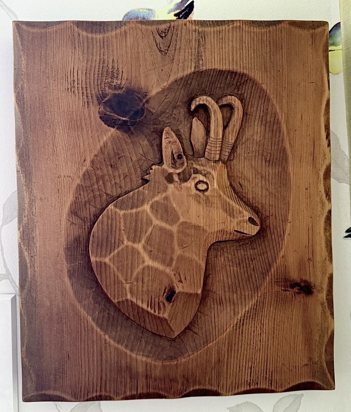 Holzschnitt mit dem Kopf einer Gämse, geschnitzt, mit markanten Hörnern und Fellzeichnung.